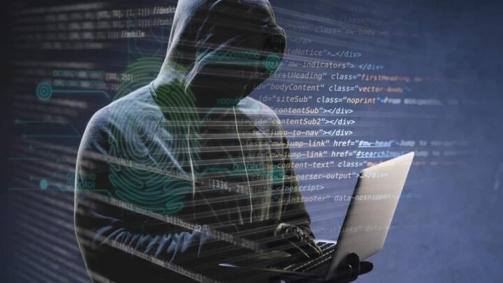 Disaster Recovery: A digital composite image featuring a silhouette of a person in a hoodie working on a laptop. The background consists of blue digital code and graphics overlaying the figure, suggesting themes of cybersecurity, hacking, or programming. The screen’s reflection is visible on the silhouette’s hood, indicating intense concentration on the task at hand.